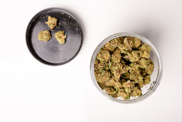 Jar full of Dry marijuana buds, cannabis dried flowers, medical marijuana, laying on the white table.