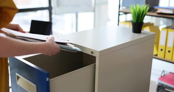 Woman manager opens metal box and puts documents in office. Storage of business documents