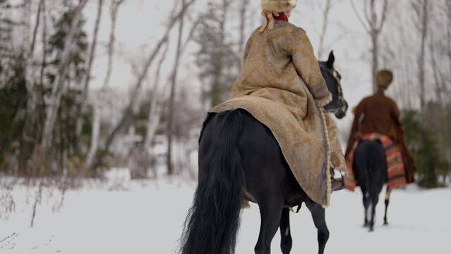 ancient historical reconstruction, people in old nobles suits riding horse in winter, back view