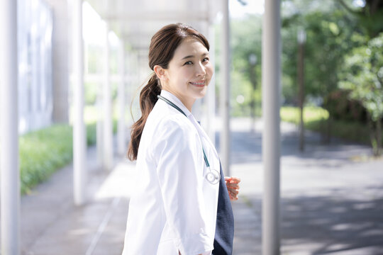 採用や転職で使えそうな逆光が美しい振り返る美しいアジア系の女医さんのイメージ　カメラ目線