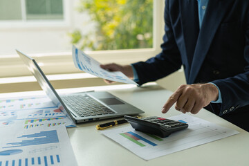 Businessmen hold graph documents to calculate financial analysis. Close-up of a businessman holding a pen while reviewing financial statements for business performance or return on investment.