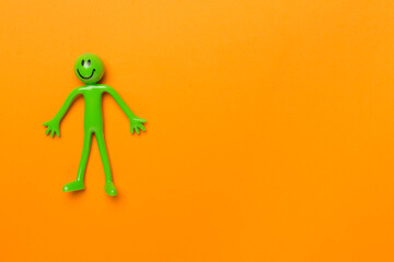 Human figure toy on color background, top view