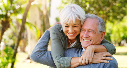 Love, hugging and elderly couple in a garden together with care, happiness and romance. Smile, nature and senior man and woman in retirement embracing, laughing and sitting in an outdoor green park.