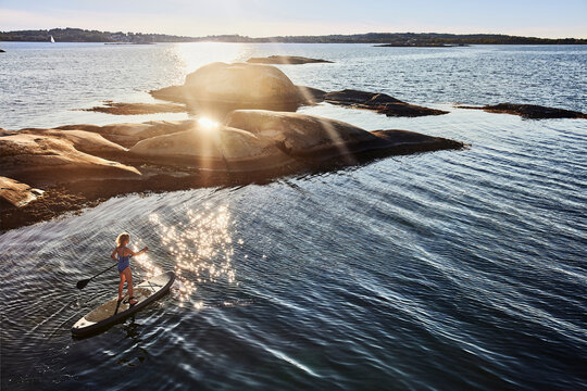 Girl paddleboarding on sea during sunset