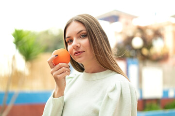 Young pretty blonde woman holding an orange