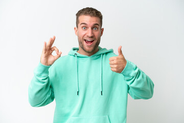 Fototapeta premium Young handsome caucasian man isolated on white background showing ok sign and thumb up gesture