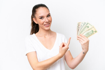 Young caucasian woman taking a lot of money isolated on white background pointing back