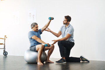 Dumbbells, physiotherapy and exercise with doctor and old man for rehabilitation, training and balance. Health, pain and healing with senior patient and physiotherapist for consulting, muscle or help - obrazy, fototapety, plakaty