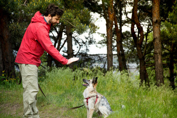 A guy in a red jacket walks his dog in the woods