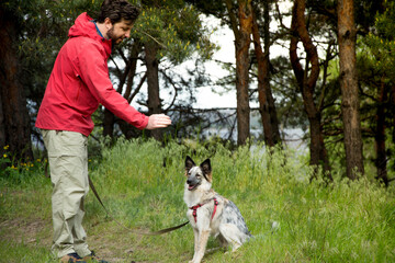 A guy in a red jacket walks his dog in the woods