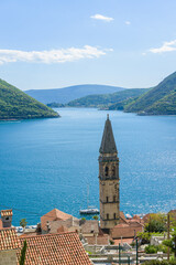 The bell tower of St Nicholas church in Perast and Verige is the strait of Boka Kotorska in the background. Montenegro - 603963127