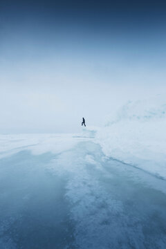 Man standing on ice by frozen lake