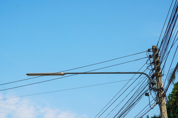 Messy electric cable in pole area lines against blue sky and cloud with copy space.