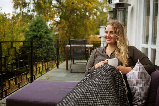 Woman sitting in chair on patio with coffee cup