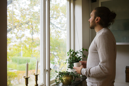Young man with coffee cup by window