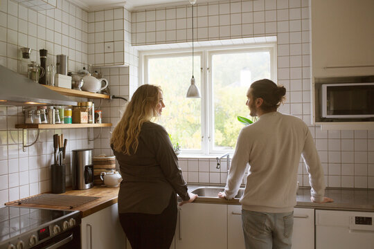 Couple standing by kitchen window