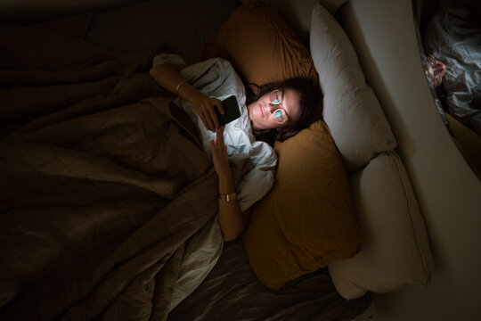 Woman using smart phone while lying in bed