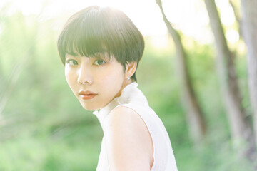 新緑背景の若い日本人女性のビューティーポートレート/自然光野外