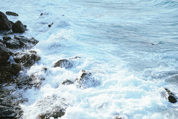 White bubble from sea water bounce with rocks on the beach in morning light. Beauty nature background.