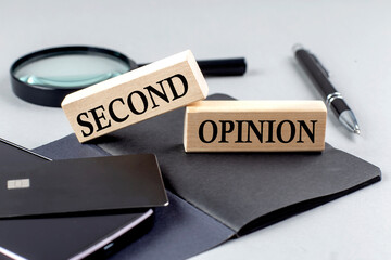 SECOND OPINION text on wooden block on black notebook , business concept