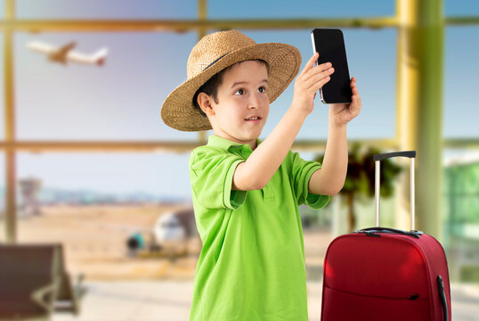 Caucasian little boy smiling making selfie by the smartphone at airport.