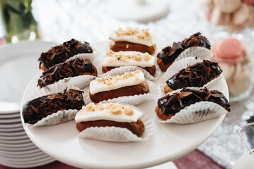 Homemade eclairs or profiteroles with custard and chocolate. Traditional french eclairs, dessert. Candy bar. Dessert table for party goodies. Party reception, decorated delicious in the restaurant.