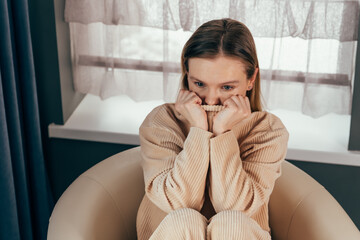 Sad thoughtful girl sits on chair feels depressed, offended or lonely. Upset young woman suffers...