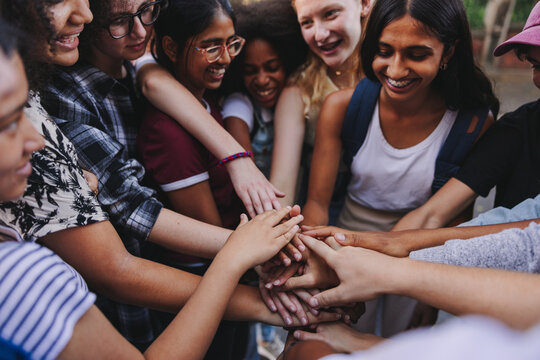 Group of multicultural teenagers putting their hands together in unity