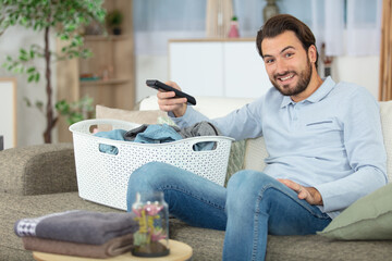man watching tv instead of doing laundry