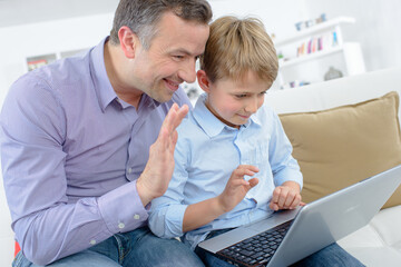 a boy and his dad waving on the laptop