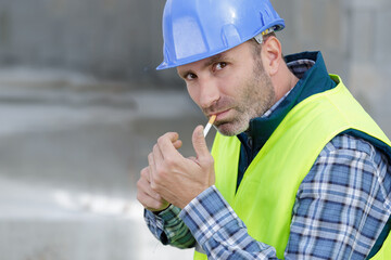 builder in hardhat and protective googles smoking cigarette