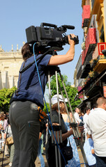 Television camerawoman recording a religious event on a street in downtown Seville, Spain