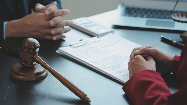 Justice and Law concept. Legal counsel presents to the client a signed contract with gavel and legal law or legal having team meeting at law firm in background