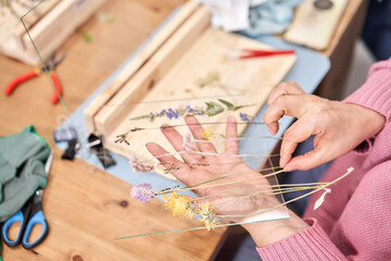 A woman lays out a composition. Master class on creating frame with Herbarium in tiffany technique...