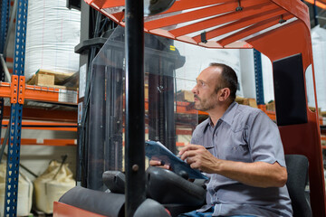factory worker with clipboard in forklift