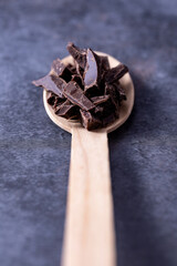 Dark chocolate broken into pieces in a wooden spoon