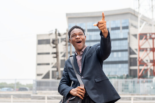 young african businessman looking amazed and pointing