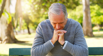 Stress, thinking and senior man in a park sitting on a bench with a contemplating face and hand...