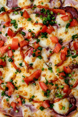Pizza with cheese, smoked meat, tomatoes, sausage and ketchup, close-up