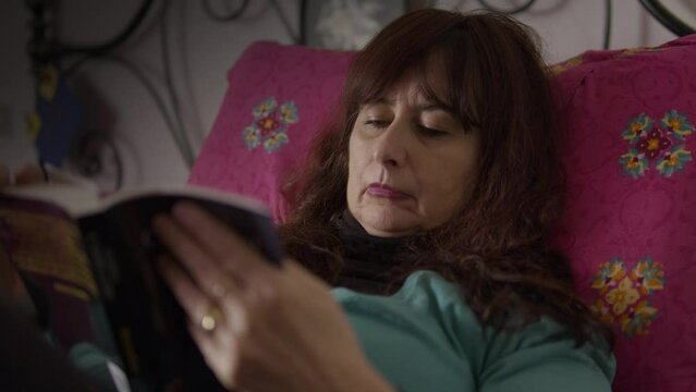 donna molto assonnata prova a leggere un libro mentre &egrave; a letto