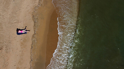A woman wearing a pink swimsuit sunbath as waves crash in Jomtien beach, located in Pattaya, a resort city near Bangkok, Thailand.