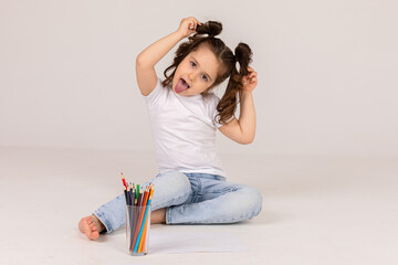 A little girl draws with colored pencils on the floor. High quality