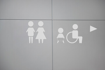 White public toilet sign with arrow showing direction on wall
