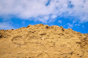 Stockpile of sand. Pile of sand with blue sky at background.