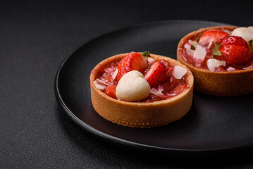 Delicious fresh sweet tartlets with strawberries and coconut flakes