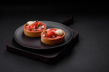 Delicious fresh sweet tartlets with strawberries and coconut flakes
