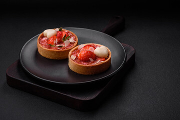 Delicious fresh sweet tartlets with strawberries and coconut flakes