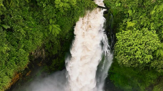 Aerial view of waterfall in the rainforest in slow motion. Telun Berasap in mountain jungle. Sumatra, Jambi, Indonesia.