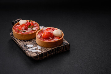 Delicious fresh sweet tartlets with strawberries and coconut flakes
