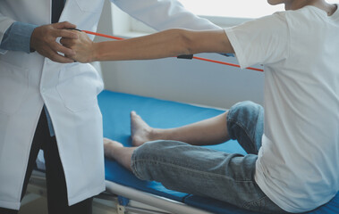 Doctor or physical therapist examines back pain and spinal area to give advice within the rehabilitation center.